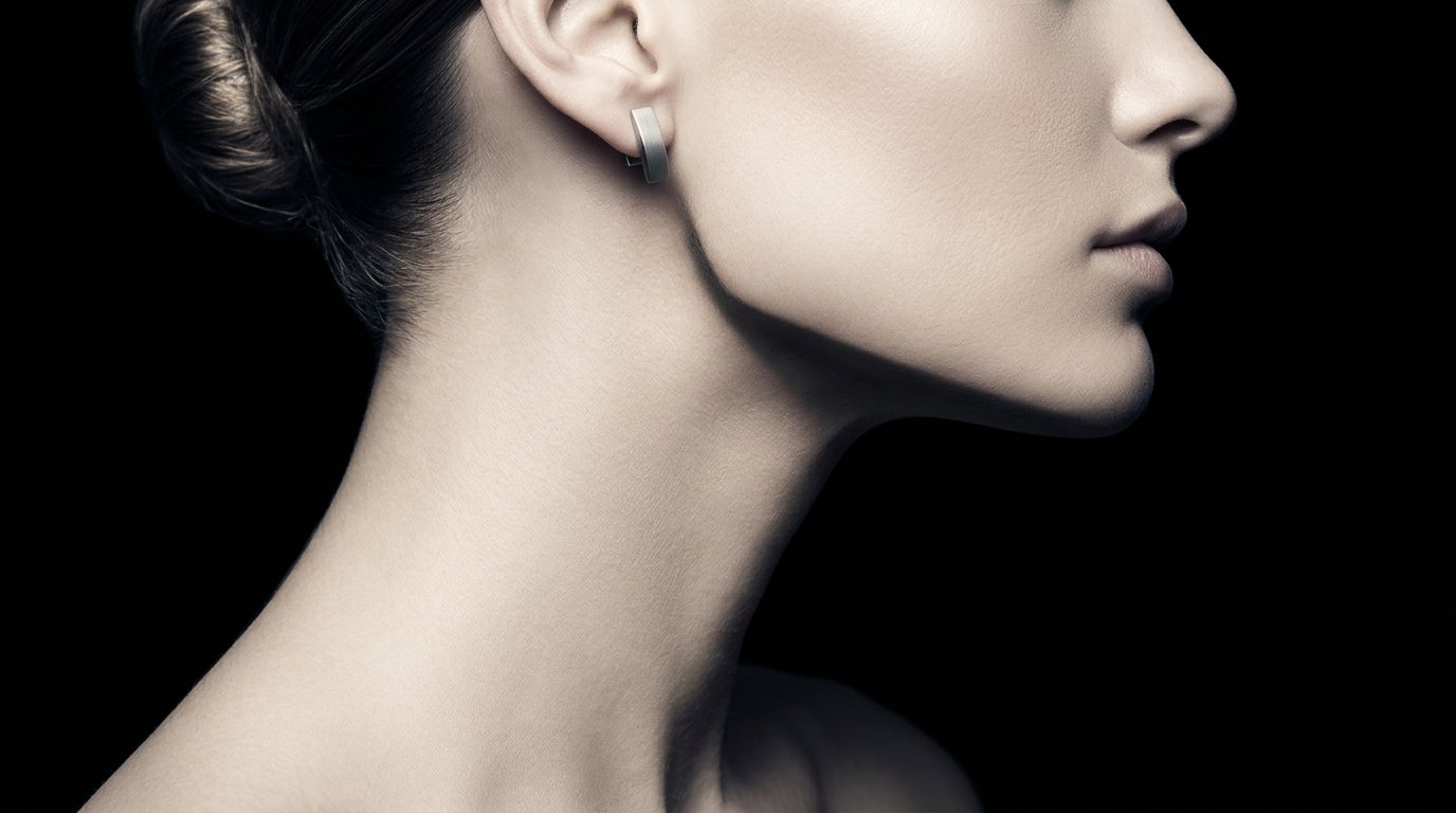 Jaw Architect — close-up jawline with dewy skin, dark editorial lighting